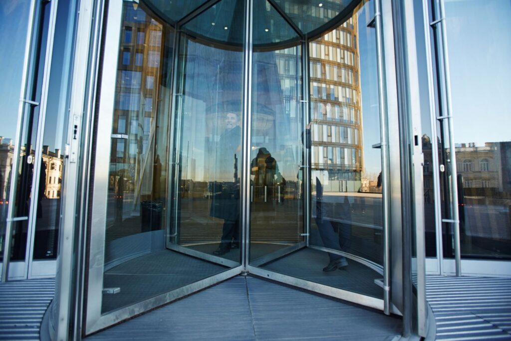 smallstoryblocks-full-length-portrait-of-senior-businessman-walking-through-revolving-door-of-office-building_rL3VsBPRZ