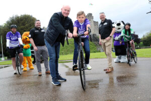 3 - Former Wales Captain Martyn Williams, Dad and cyclist Matt Evans, cyclist Gareth Williams, 9-year-old Hywel Evans, C2Cycling Director Nick Robbins, cyclist Ellie Jones and Velindre and Latch Mascots