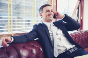 smsmiling-businessman-sitting-and-talking-on-the-phone-at-office