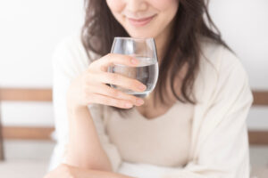 ベッドで水を飲む女性