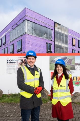 A couple of people wearing safety vests and helmets posing for the cameraDescription automatically generated with low confidence