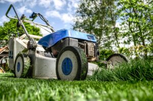 Close-up view of a lawn mower cutting grass in a garden on a sunny day.