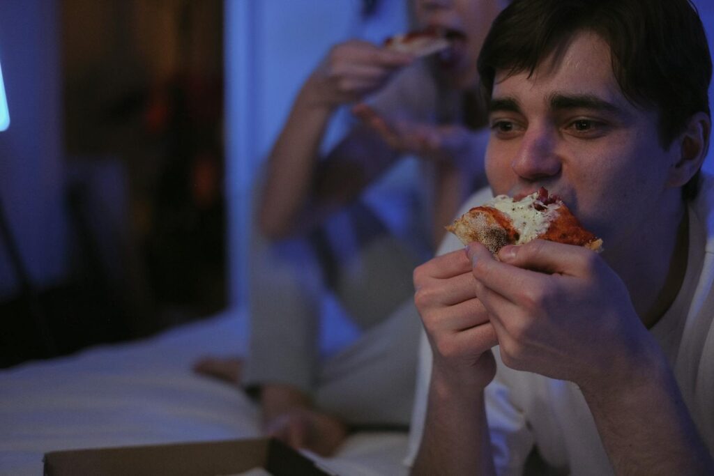 Group of adults enjoying pizza indoors during a casual evening.