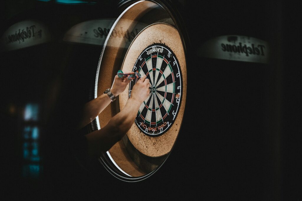 person picking dart pins on board