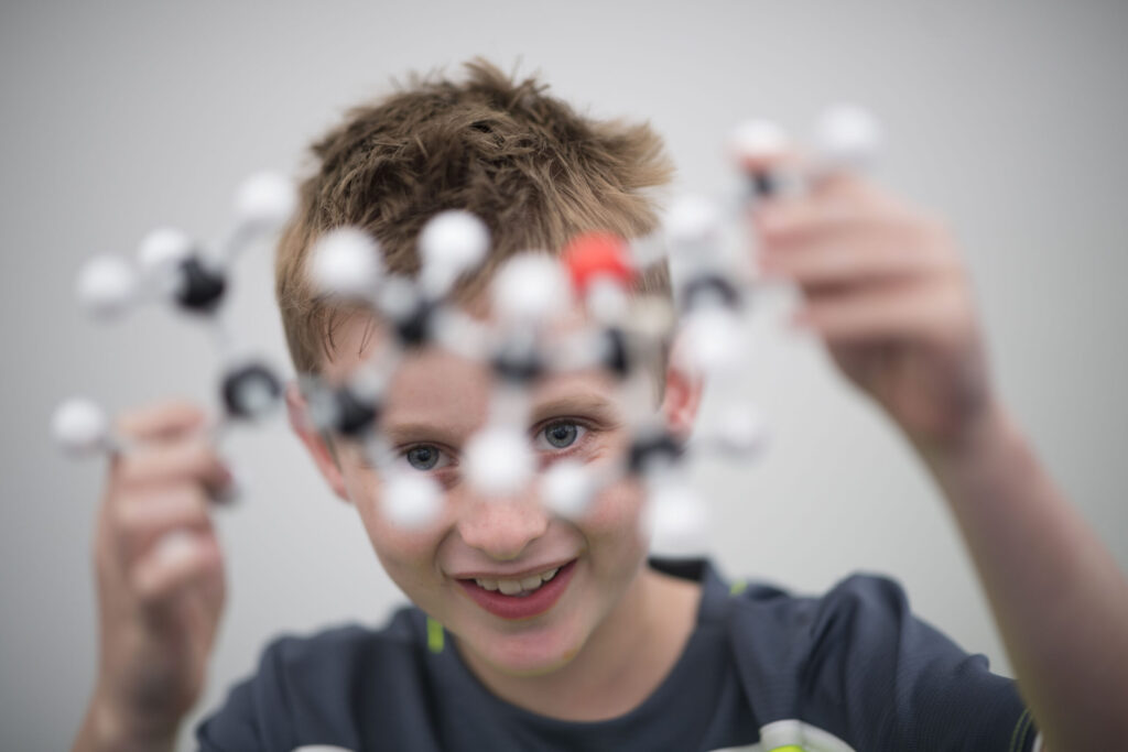 A young boy looks through a molecular structure