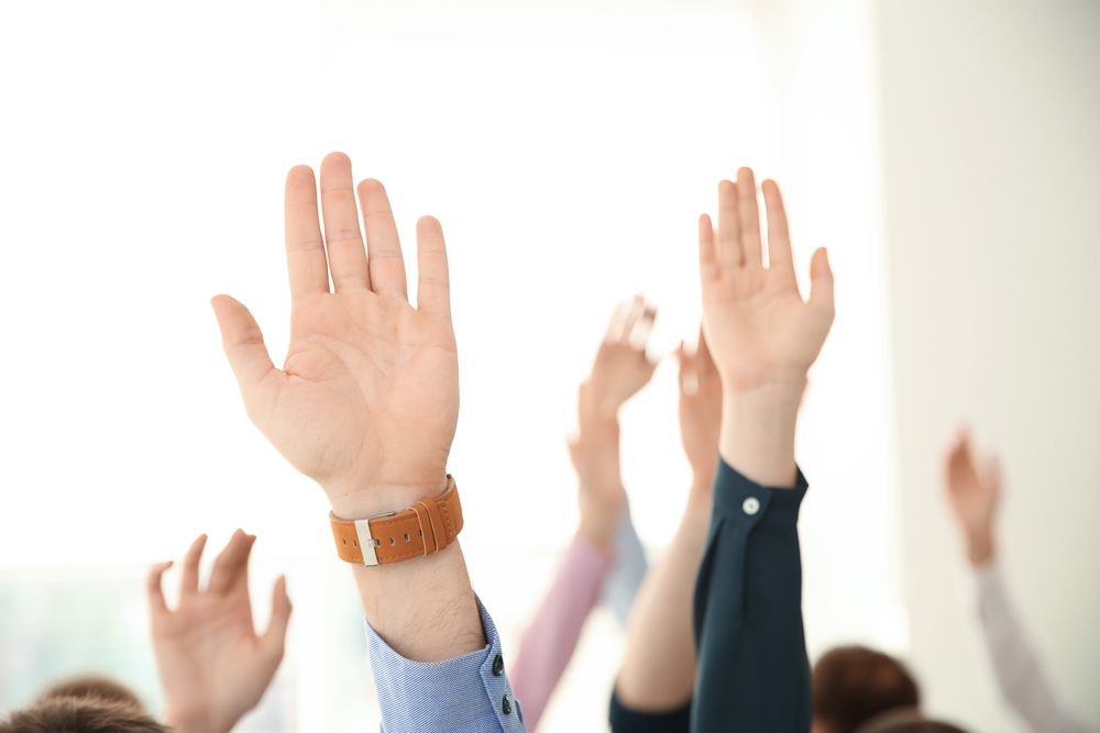 People raising hands to ask questions at business training on li