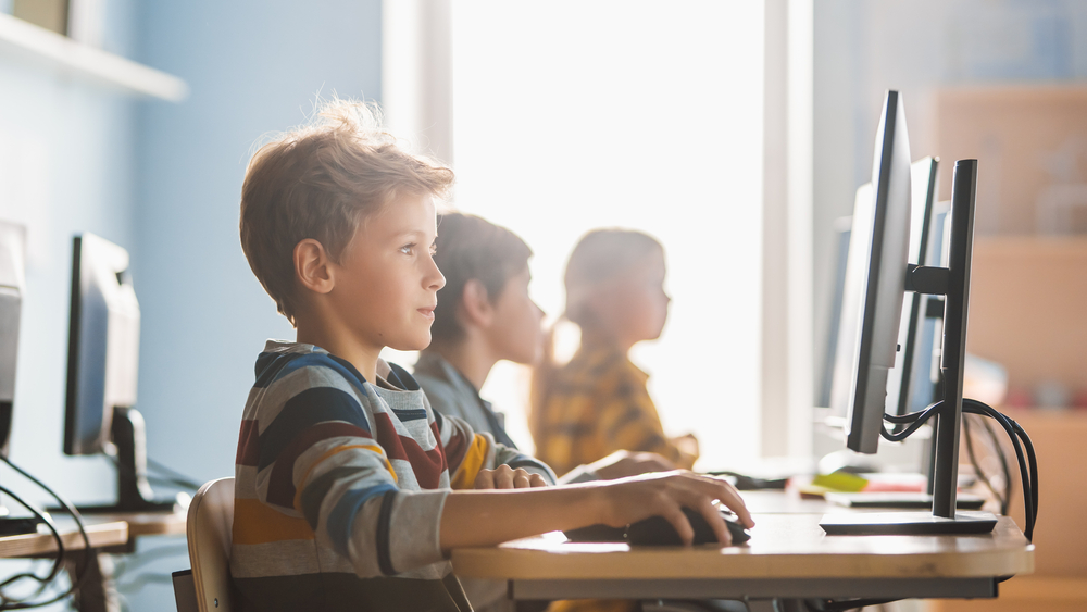 Elementary School Computer Science Classroom: Smart Little Schoolboy Works on Personal Computers, Learning Programming Language for Software Coding. Schoolchildren Getting Modern Education