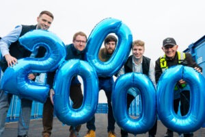 A group of people standing with blue balloons in the shape of 20,000