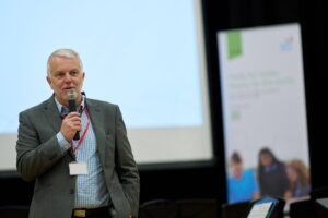 Ian Morgan holding a microphone and speaking at the WJEC's launch event.