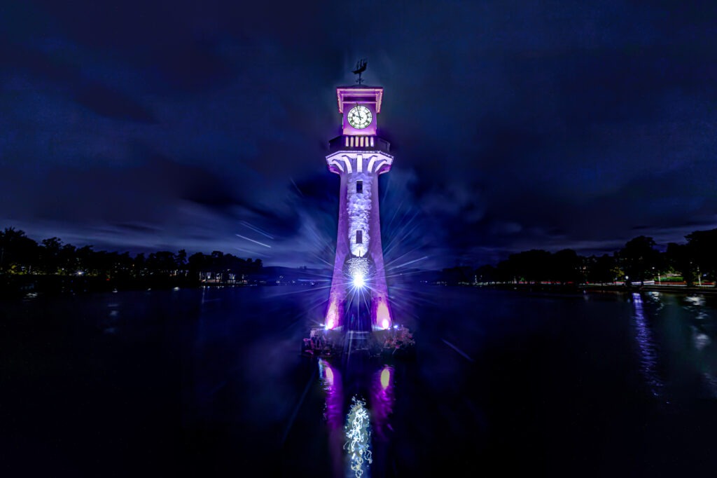 A photo taken at night of Roath Park's lighthouse lit up in City Hospice purple for the Light Up A Life appeal.