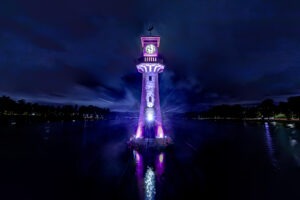 A photo taken at night of Roath Park's lighthouse lit up in City Hospice purple for the Light Up A Life appeal.