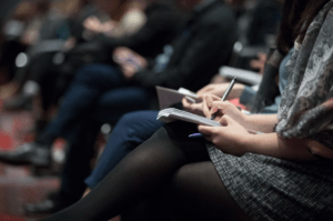 A close up of a woman taking notes at a business event.