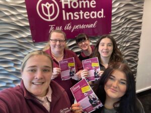 The Home Instead team holding flyers for the launch of their wellbeing café.