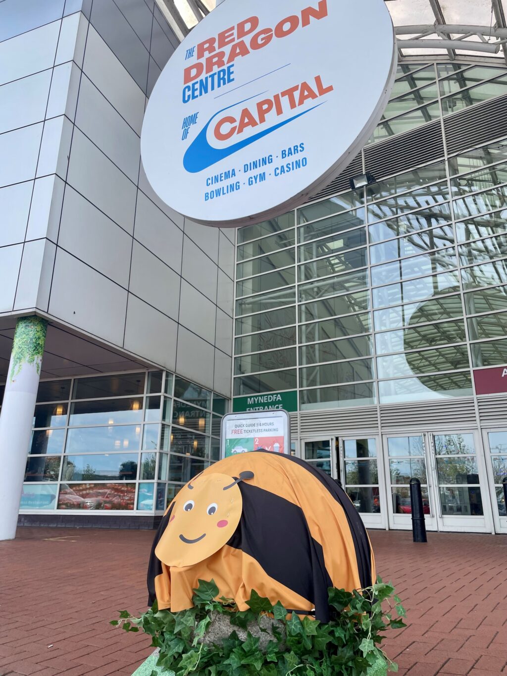 The outside of The Red Dragon Centre in Cardiff Bay with a Bee model outside the building.