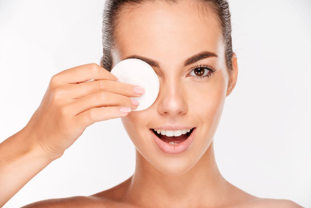 a-graphicstock-laughing-beautiful-young-woman-holding-round-white-cotton-pad-to-her-eye--SBI-302779372