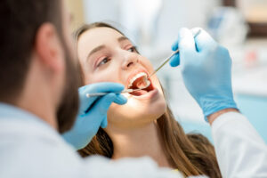 dentist-examining-patient-teeth-with-mouth-mirror-dental-excavator-close-up-view-woman-s-face