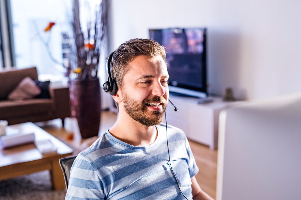 graphicstock-man-sitting-at-the-desk-working-from-home-on-computer-wearing-headseat-talking-on-the-phone_r_aWKrBf-