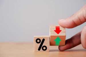 Hand flipping wooden cube block to change between up and down with percentage sign symbol.