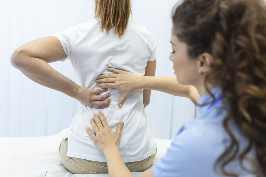 Physiotherapist doing healing treatment on womans back. Back pain patient, treatment, medical doctor, massage therapist.office syndrome